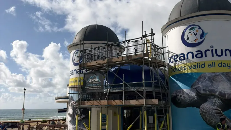 Access scaffold with mesh guards around the entrance of Bournemouth Oceanarium, between its two domed towers on Bournemouth seafront