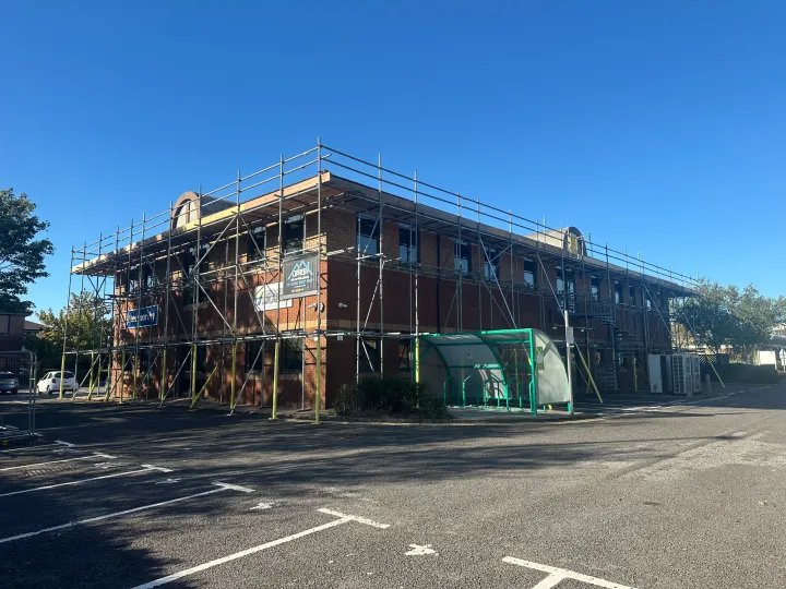 Scaffolding around the corner and side of a brick commercial building at New Fields Business Park, Poole