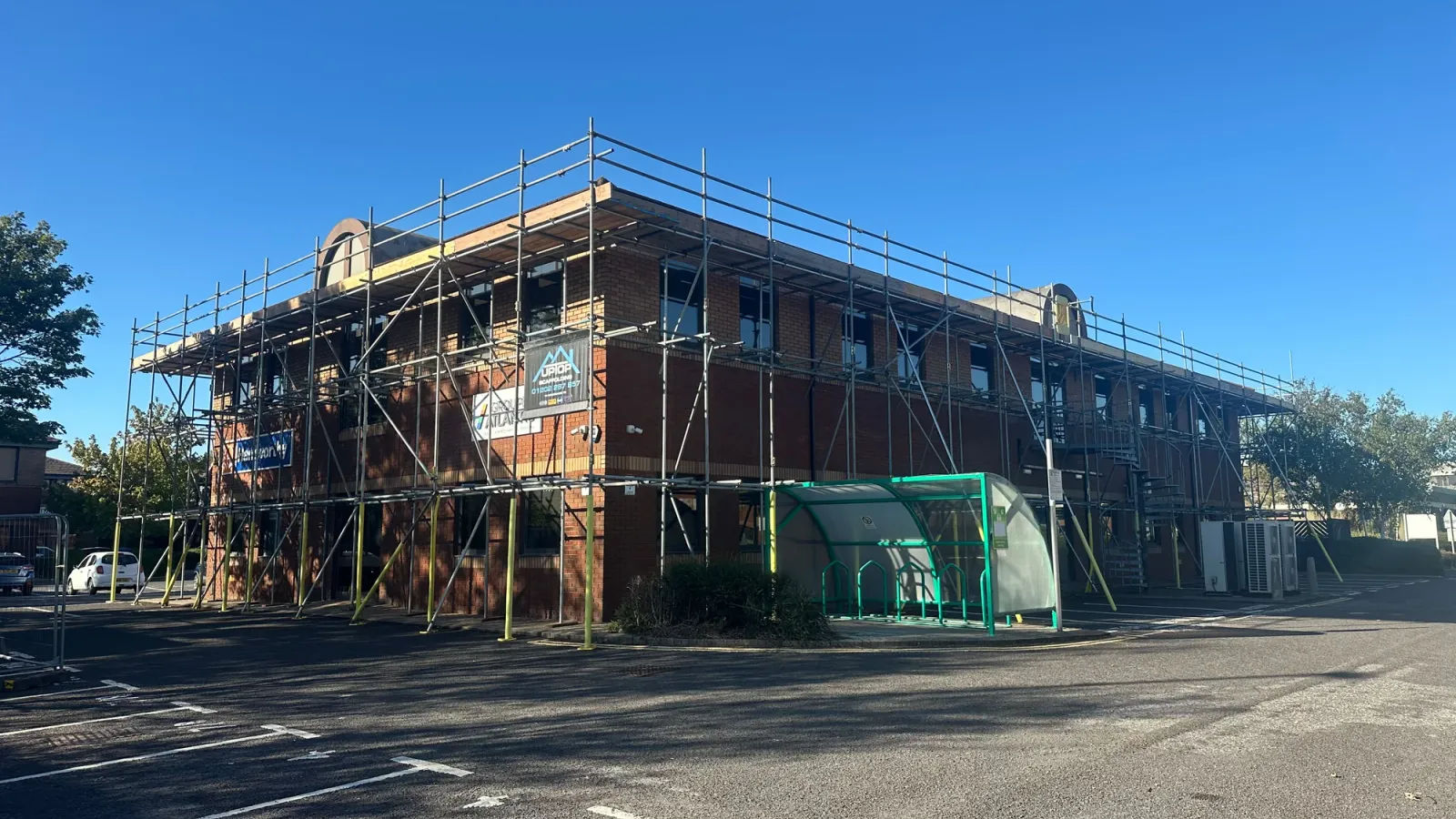 Scaffolding around the corner and side of a brick commercial building at New Fields Business Park, Poole