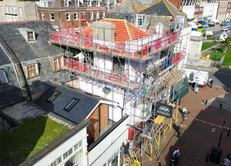 Scaffold platform view showing roof structure and safety rails during Weymouth roofing works.